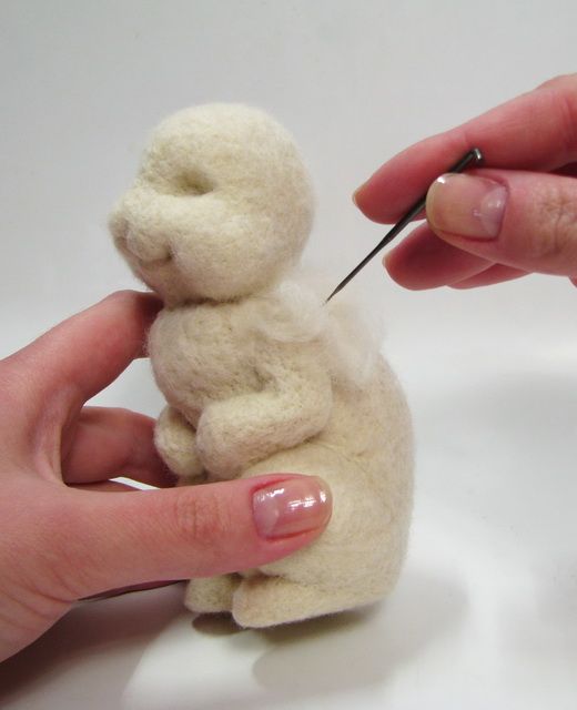 someone is needleing the end of a small stuffed animal