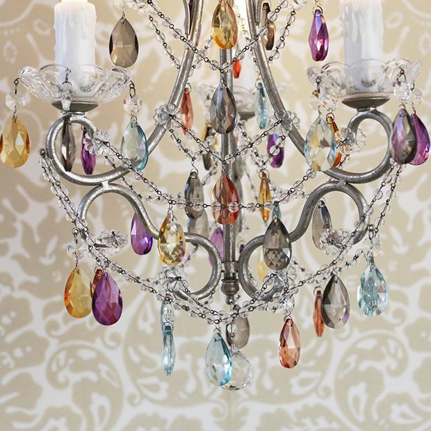 a crystal chandelier with candles in the middle and colorful crystals hanging from it