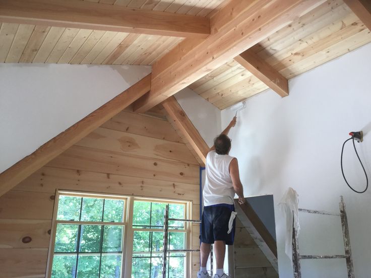 a man standing on top of a ladder painting the ceiling