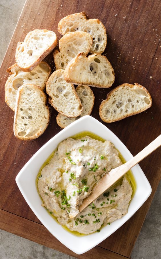 some bread slices and dip in a bowl on a table