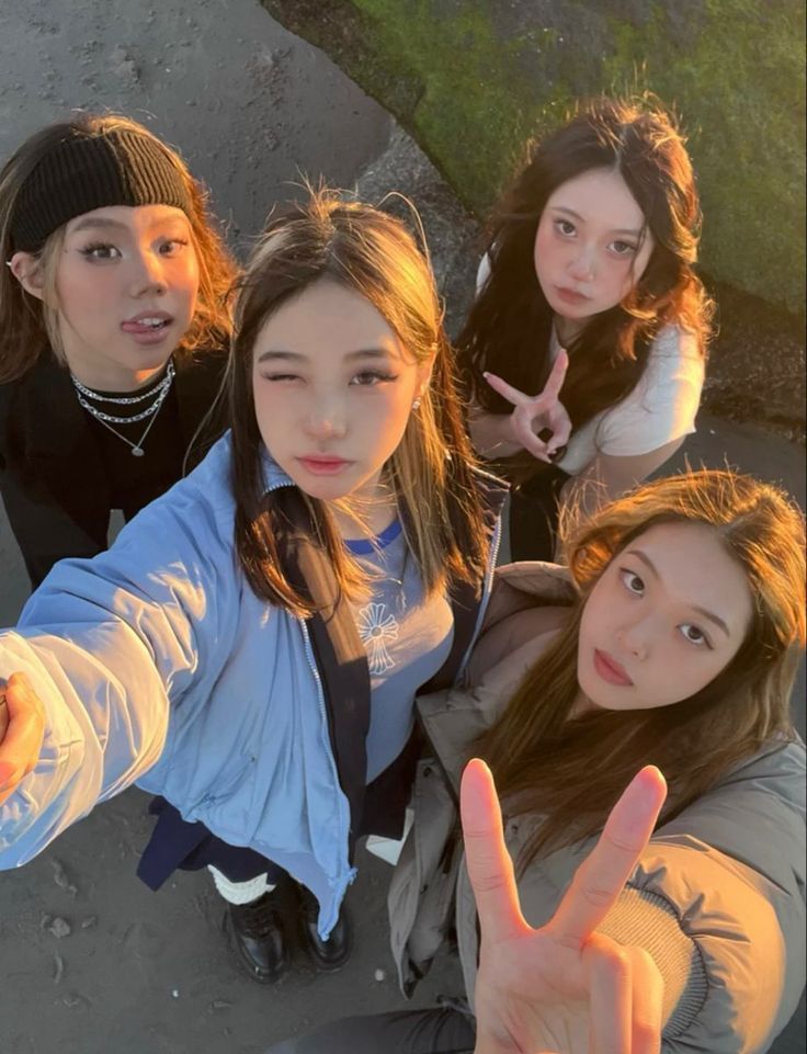 three young women standing next to each other giving the peace sign with their fingers in front of them