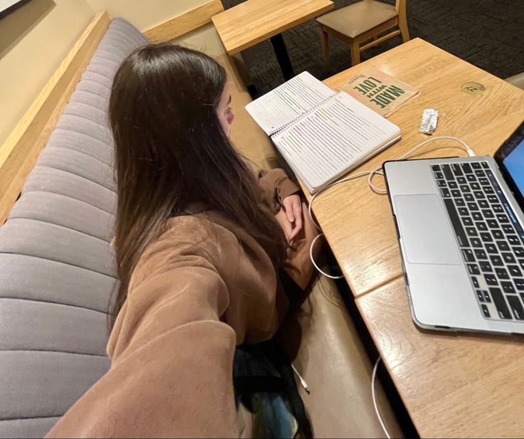 a woman sitting at a table with a laptop computer on her lap and papers in front of her