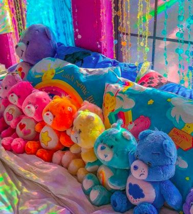 there are many colorful stuffed animals on the bed and in front of them is a pillow