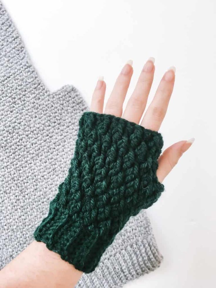 a woman's hand wearing a green knitted wrist warmer