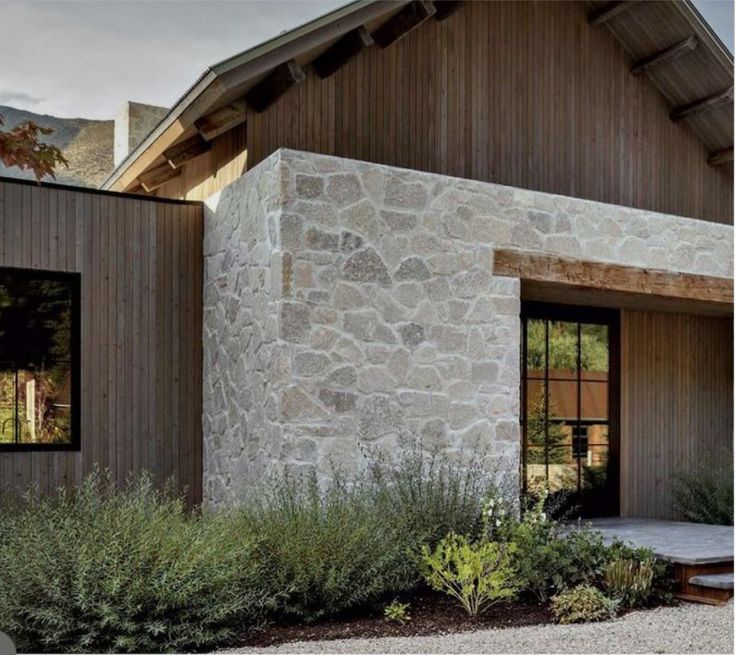 a stone house with wooden siding and windows