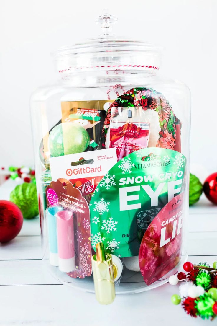 a glass jar filled with christmas items on top of a table