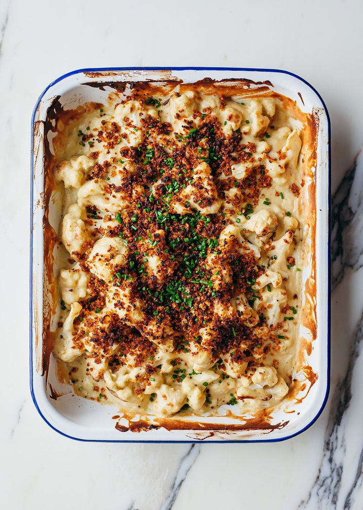 a casserole dish filled with macaroni and cheese topped with parsley