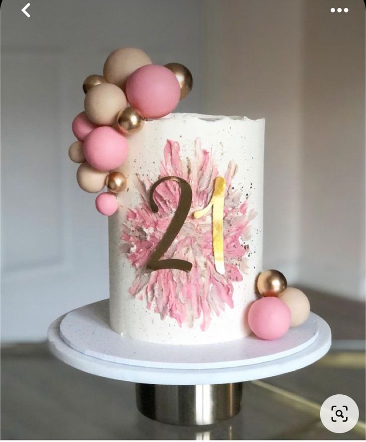 a white cake with pink and gold decorations on it's side, sitting on top of a table