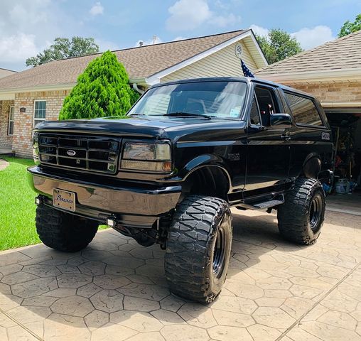 a large black truck parked in front of a house next to a driveway and grass