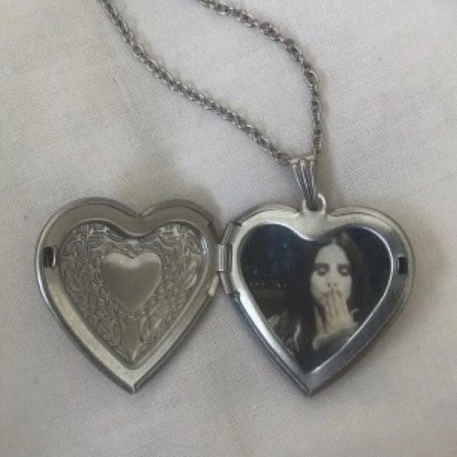 two heart shaped lockes are shown on a white cloth background, one is holding a photo and the other has a chain attached to it