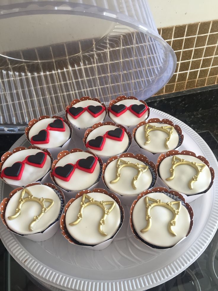 cupcakes with white frosting and red icing are arranged on a plate