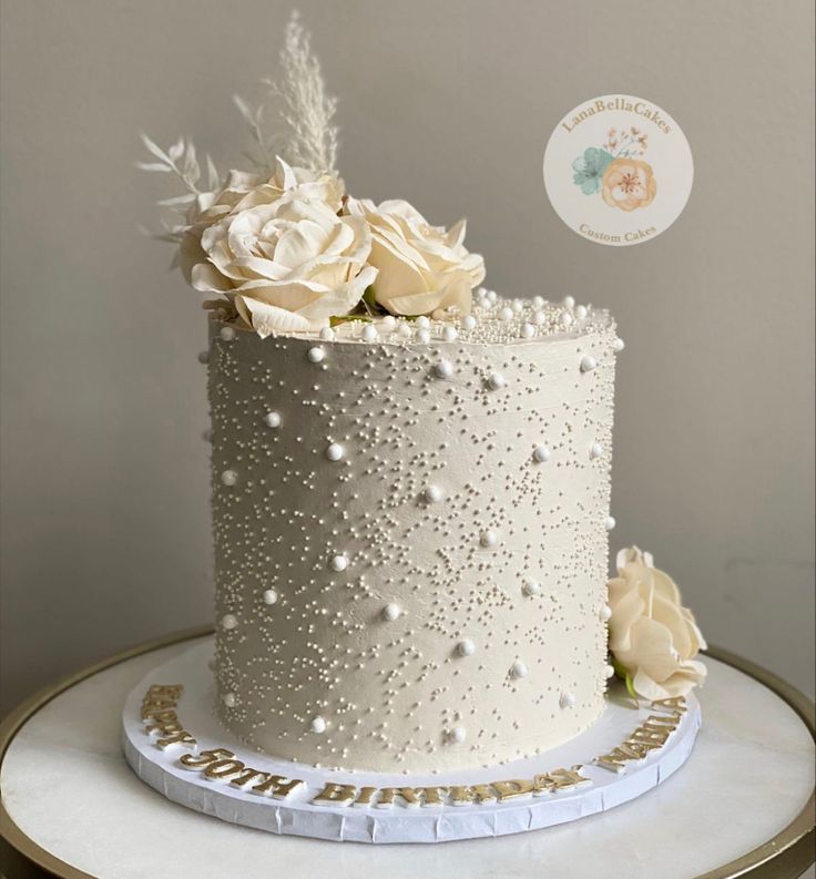 a white wedding cake decorated with pearls and flowers