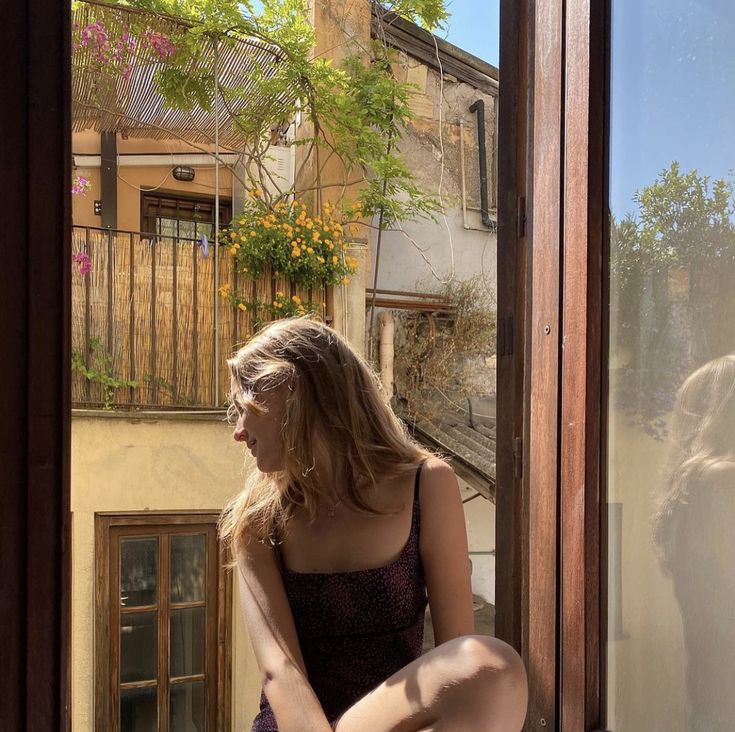 a woman sitting on a window sill looking out the window