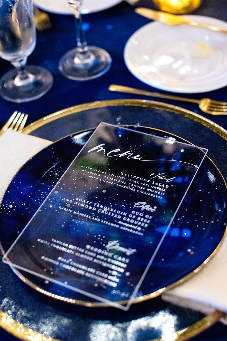 a blue and gold dinner table setting with menus