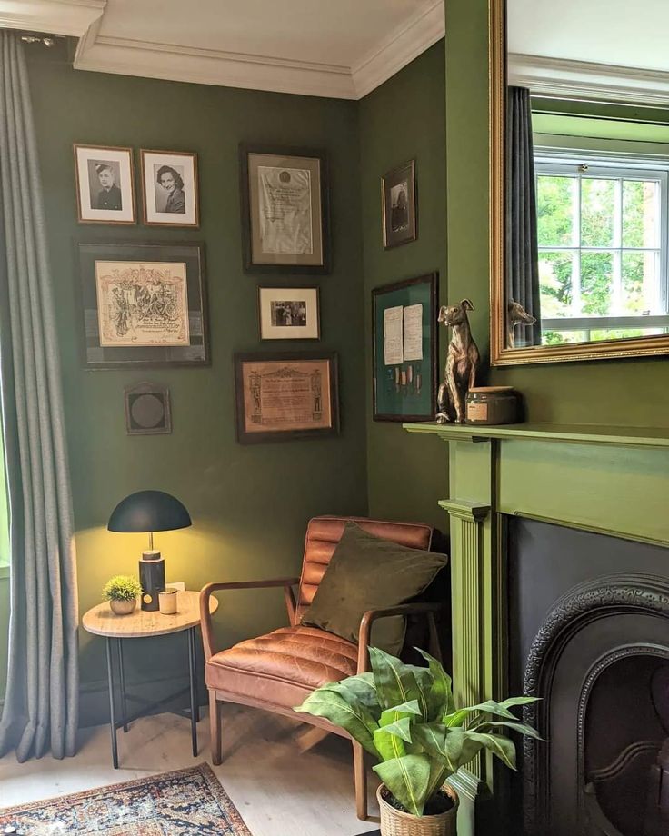 a living room with green walls and pictures on the wall next to a fire place