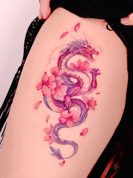 a woman's thigh with flowers and a dragon tattoo