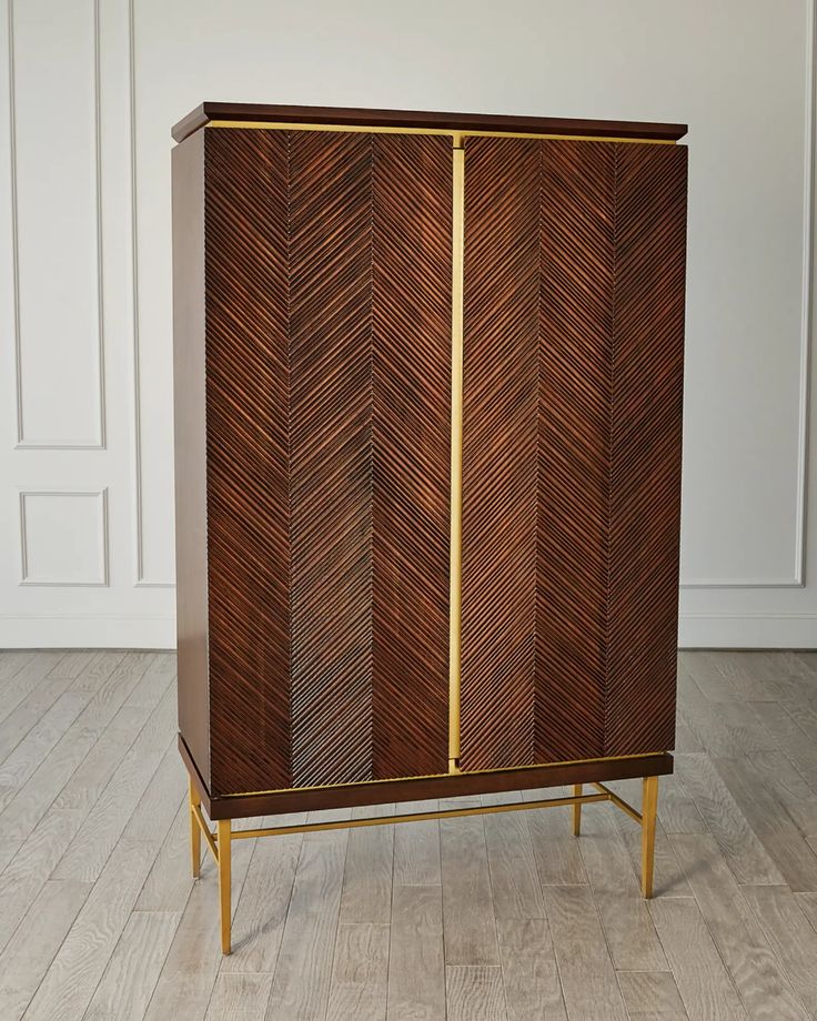 a wooden cabinet with gold trim and an arrow pattern on the front, against a white wall