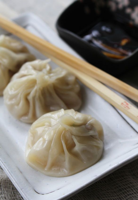 three dumplings on a plate with chopsticks next to them