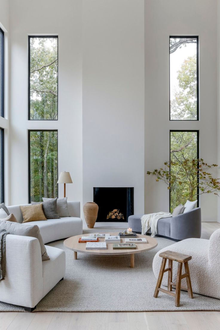 a living room filled with white furniture and large windowed windows next to a fire place