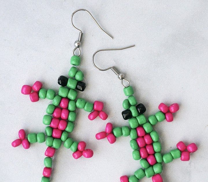 two green and pink beaded earrings sitting on top of a white table next to each other