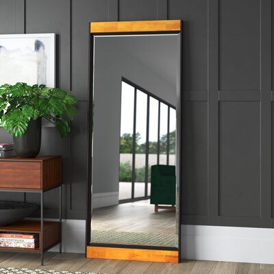 a large mirror sitting on top of a wooden dresser next to a plant in a vase