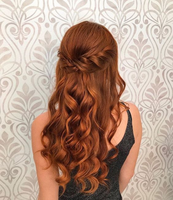 a woman with long red hair is standing in front of a wall