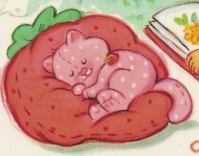 a pink teddy bear sleeping on top of a red pillow next to an open book