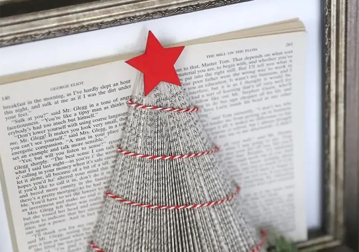 an origami christmas tree made out of book pages is displayed in a frame