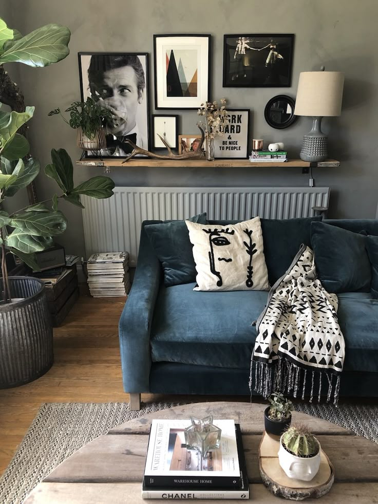 a living room with blue couches and pictures on the wall above them, along with potted plants