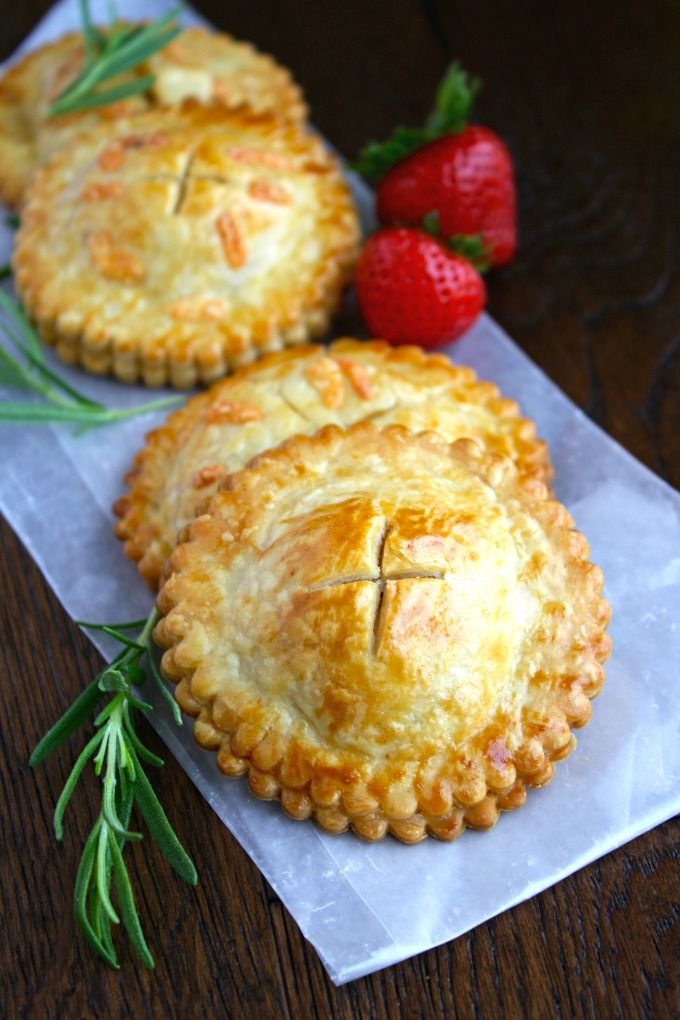 two small pies sitting on top of a piece of paper next to strawberries