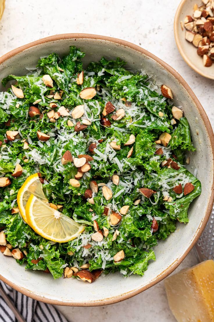 a bowl filled with kale salad and topped with lemon wedges