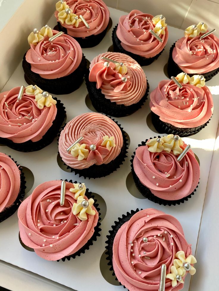 twelve cupcakes with pink frosting in a box