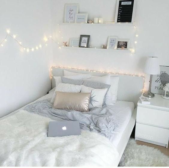 a bedroom with white walls and lights on the headboard is decorated in neutral colors