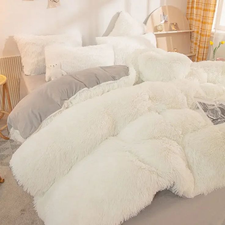 a bed covered in white fluffy blankets and pillows