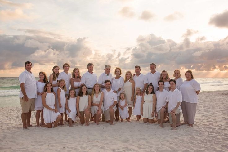 a large group of people standing on top of a sandy beach next to the ocean