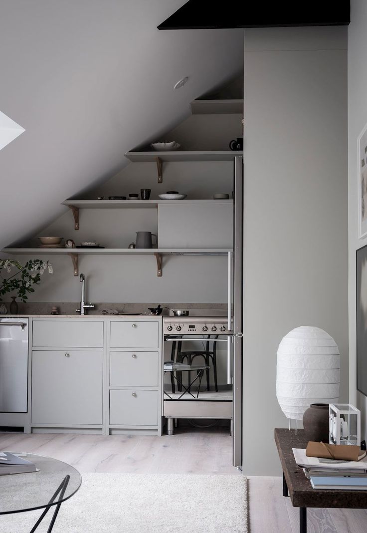 an attic kitchen with white cabinets and stainless steel stove top oven in the middle of the room