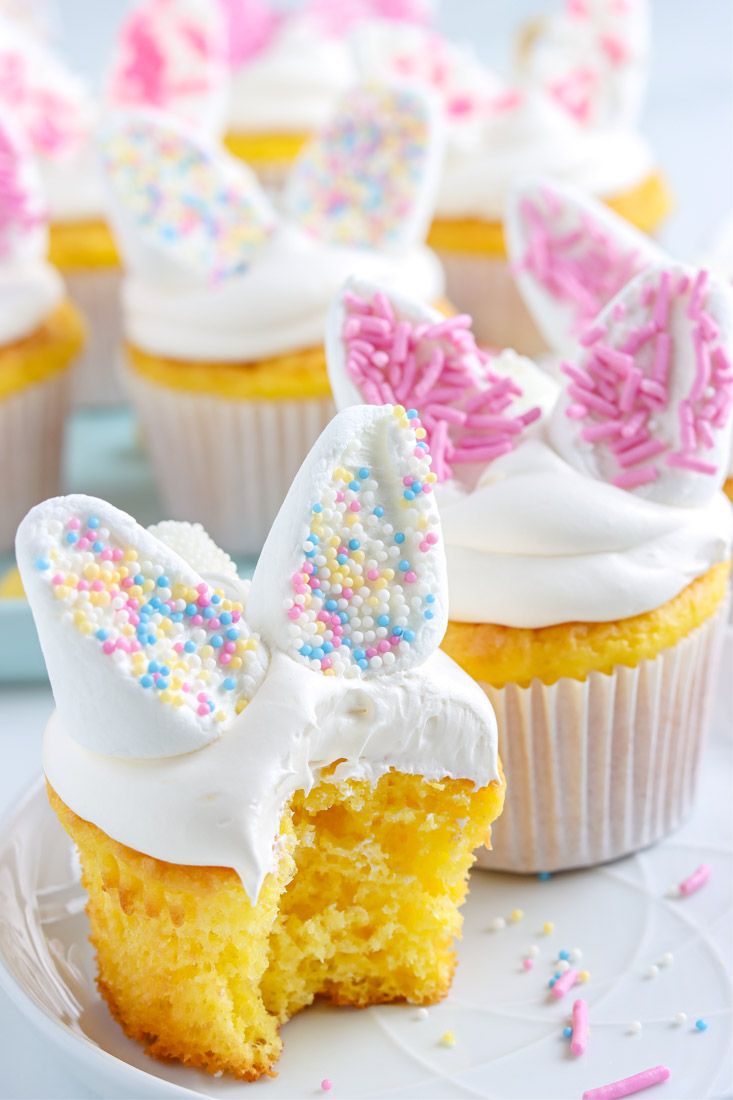 cupcakes with white frosting and colorful sprinkles are on a plate