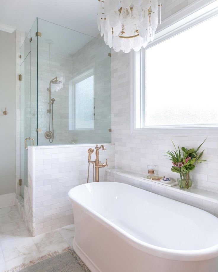 a white bath tub sitting under a window next to a sink and shower faucet