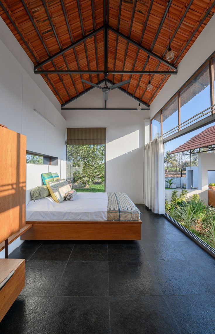 a bed sitting under a wooden roof in a bedroom next to a large glass window