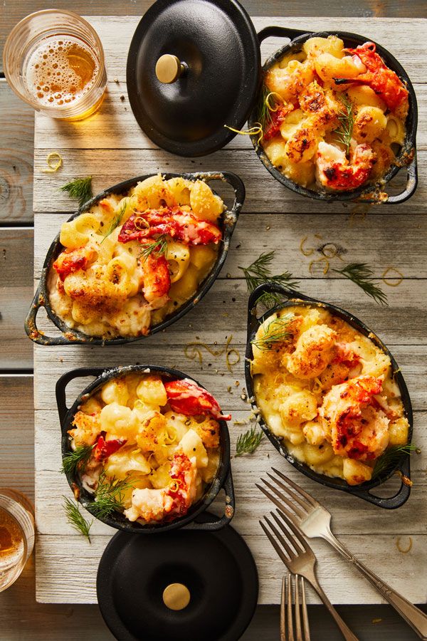 four cast iron skillets filled with food on top of a wooden table next to utensils