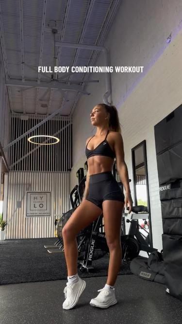 a woman standing in a gym with her legs crossed