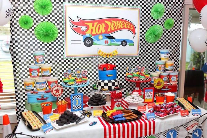 a birthday party with cars and hot wheels decorations on the table, including candy bars