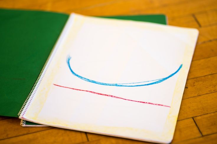 two notebooks sitting next to each other on top of a wooden floor with colored pencils