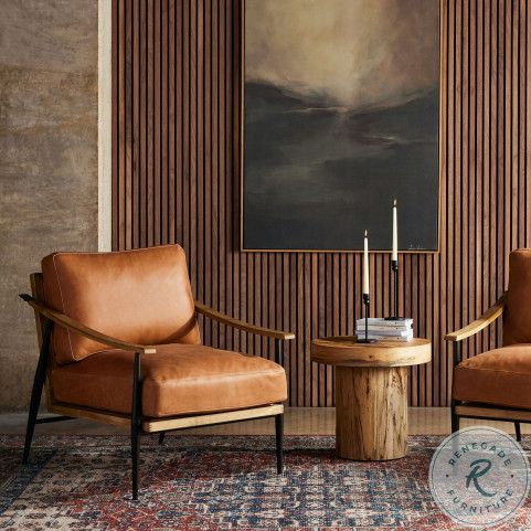 two brown chairs sitting next to each other in front of a painting on the wall