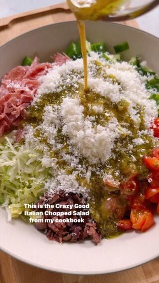 a bowl filled with meat and vegetables covered in grated parmesan cheese being drizzled over it