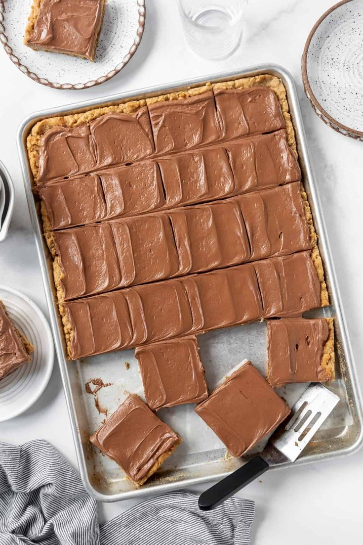 a pan filled with chocolate frosting next to other desserts and utensils