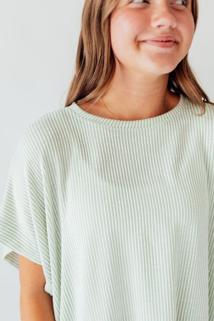 Experience comfort and style with the Journee Top. Its light green color with white stripes adds a touch of freshness, while the dolman sleeves and straight hem provide a relaxed fit. Perfect for any casual outing or lounging at home. Elevate your wardrobe with this versatile and chic top! Fits true to size. Model is wearing a small and is 5'3". Plus model is wearing a 1X and is 5'8". Size Chart Length Bust S 22" 48" M 22" 50" L 23" 48" 1x 24" 52" 2x 24" 54" 3x 25" 56" *All measurements are appr Green Short Sleeve Tops For Lounging, Spring Oversized Top With Striped Hem, Green Ribbed Top For Loungewear, Oversized Spring Top With Striped Hem, Oversized Striped Hem Tops For Spring, Relaxed Striped Tops For Spring, Oversized Tops With Striped Hem For Spring, Comfortable Green Summer Tops, Short Sleeve Tops For Spring Lounging