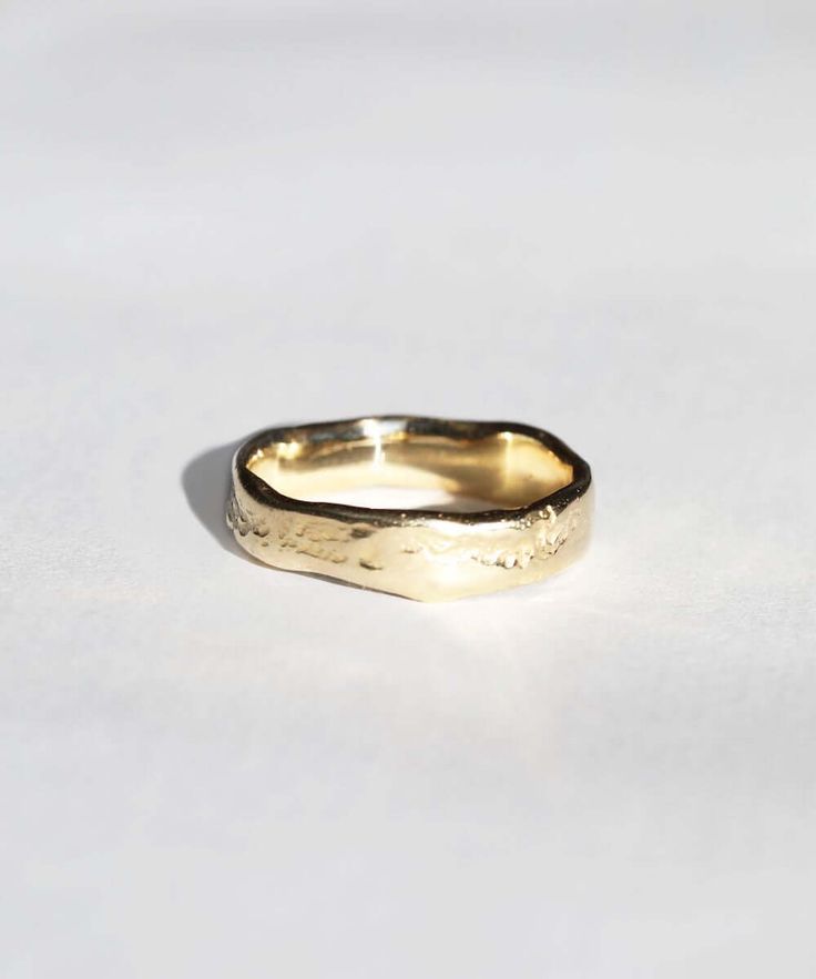 a gold wedding ring on a white surface