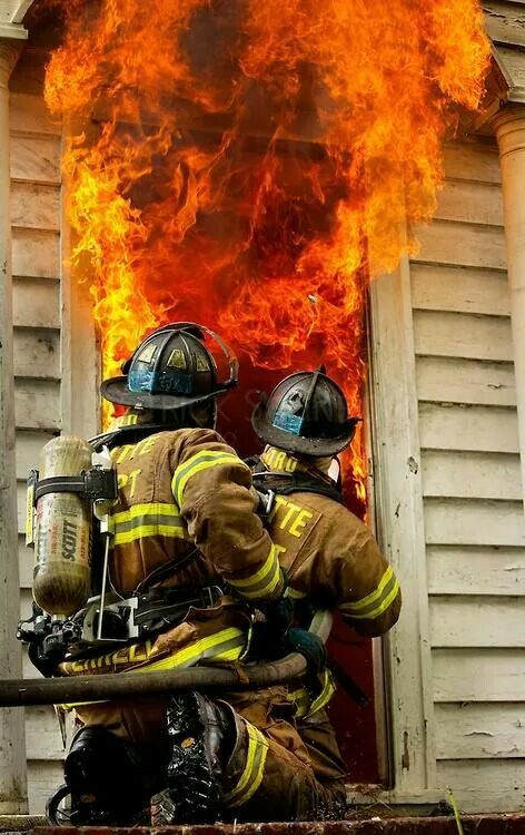 two firemen in front of a burning house