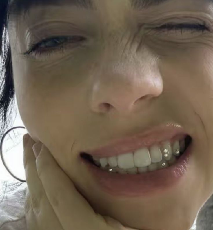 a close up of a person smiling with her hand on her chin and mouth open